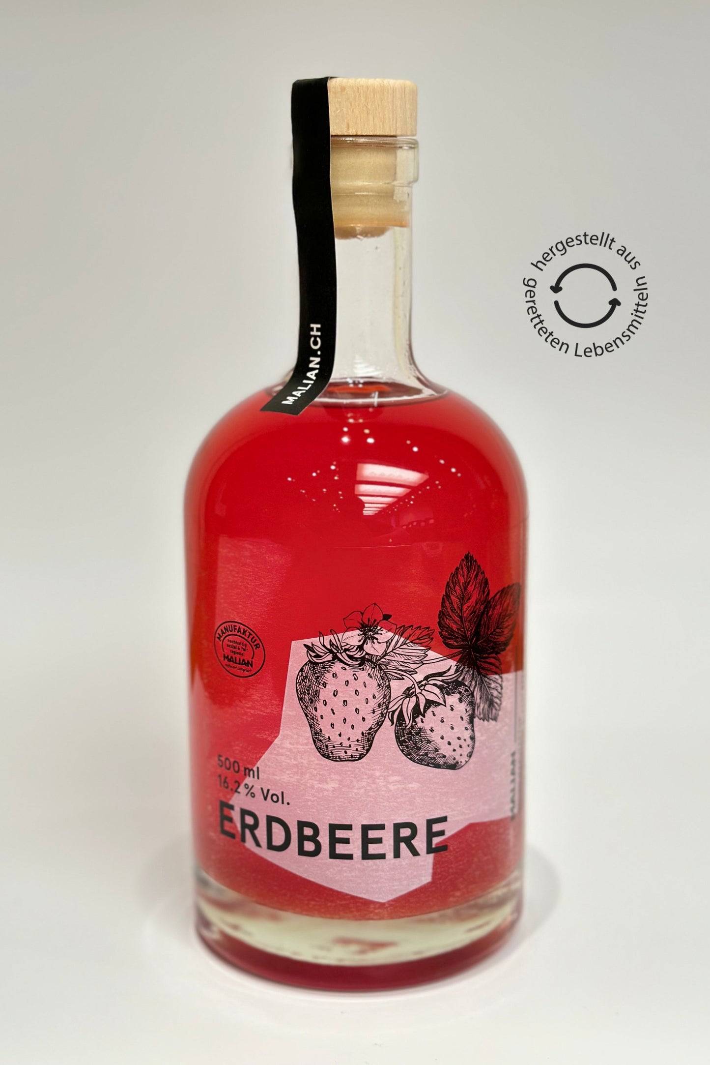 rot-pink leuchtender Erdbeerlikör. Handgemacht in der MALIAN Manufaktur Basel. Eine 0,5L Glasflasche mit Holzdeckel. Hergestellt aus geretteten Erdbeeren, da wir aktiv gegen Food Waste sind.